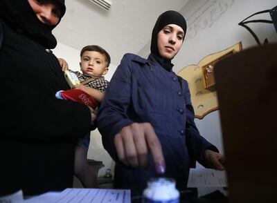 A woman in eastern Ghouta, recently recaptured by the regime, dips her index finger in ink after casting her ballot for Syria's first local elections since 2011. AFP