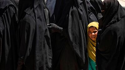 A girl stands in line to receive aid with a group of women at the Kurdish-run Al Hol camp in north-east Syria where families of ISIS foreign fighters are held, on August 18, 2020. AFP