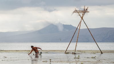 A man fishes as the Taal volcano spews smoke in Balete, Batangas on January 17. EPA