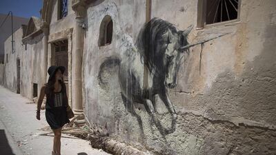 A woman looks at a mural by South African artist Faith 47. Joel Saget / AFP Photo