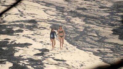 Girls walk past ash washed up on a beach where people took shelter during a fire on New Year's Eve in Mallacoota, Australia. Reuters