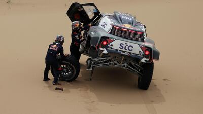 Stephane Peterhansel and Edouard Boulanger change a tyre during Stage 11. Reuters