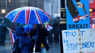 Brexit protesters shelter under an umbrella outside the Houses of Parliament. EPA
