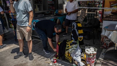 A man lights a candle at a makeshift memorial at the place where a Greek football fan was stabbed to death in Athens. AFP