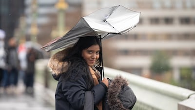 A person walks during heavy rain on Westminster Bridge. PA