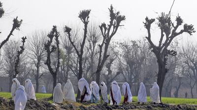 Women walk near the site of an attack on the outskirts of Peshawar, Pakistan, on February 12, 2014. Militants killed several members of an anti-Taliban militia in the northwestern city, police said. Mohammad Sajjad / AP photo