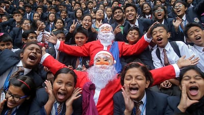 Children cheer around men dressed as Santa Claus during Christmas celebrations inside their school in Agartala, India. Reuters