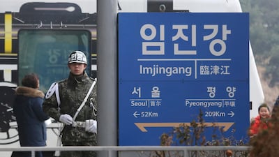 In this January 14, 2018 photo, a South Korean army soldier stands guard next to a signboard showing the distance to North Korea's capital Pyongyang and to South Korea's capital Seoul. Ahn Young-joon / AP