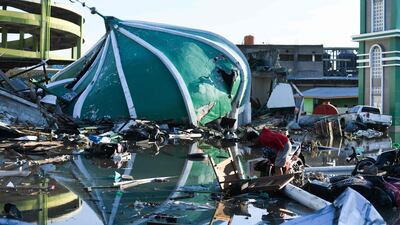 An earthquake survivor salvages items in the rubble near a collapsed mosque in Palu in Indonesia's Central Sulawesi. AFP