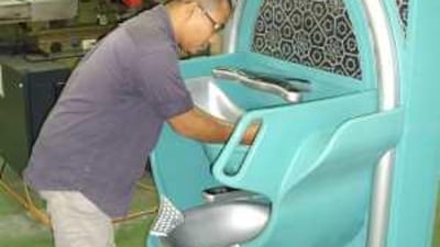 An AACE Technology employee demonstrates how to use the Auto Wudu Washer.