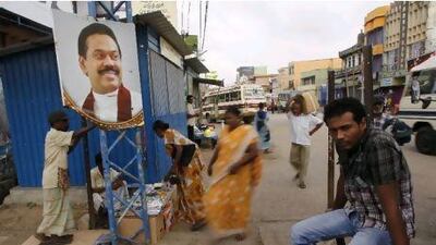 A portrait of Sri Lanka’s president, Mahinda Rajapaksa, is displayed on a post as ethnic Tamils wait next to the image in Jaffna, in the north of the island.
