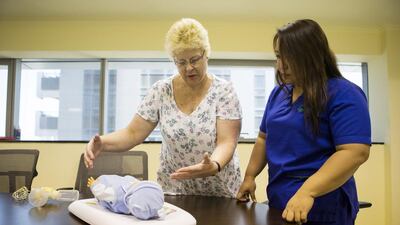 Christine Woolmer, programme manager, trains a nursing staff on how to care for an infant at the Manzil Health Care office. Christopher Pike / The National