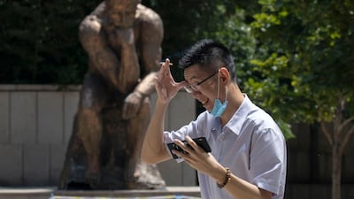 A man lowers his mask to smoke as he passes by a statue in Beijing, China. AP Photo