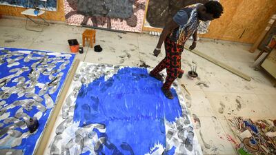 Senegalese artist Omar Ba walks over a large canvas while wearing ink-dipped sandals at his studio in March. Cooper Inveen / Reuters