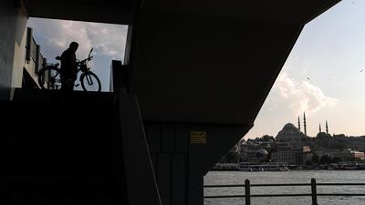 A man carries his bike under the Galata Bridge with the Suleymaniye Mosque in the while background, amid the ongoing pandemic in Istanbul, Turkey. EPA