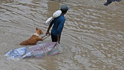 A man carries a dog to safety after heavy monsoon rain hit India's capital. AFP