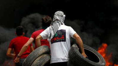 A Palestinian demonstrator carries tyres to be set ablaze during a protest in the Israeli-occupied West Bank. Reuters