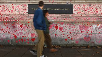 Pedestrians pass the National Covid-19 Memorial Wall, opposite the Palace of Westminster, in London. EPA