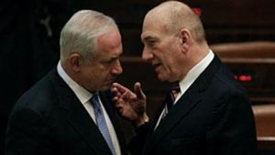 Israel's outgoing premier Ehud Olmert, right, speaks to prime-minister designate Benjamin Netanyahu before the start of the swearing-in of the latter's new coalition government in the Knesset.