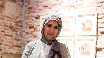 Rows of low uniform wooden columns in an installation by Eiman Elgibreen revealed human female faces underneath when visitors lifted the columns, a commentary on public uniformity in Saudi society. Elgibreen poses with her work at 'Rhizomas: Generation in???