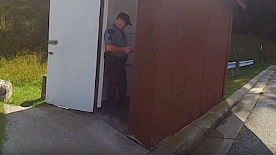 An officer stands in the doorway of an outhouse in Michigan after a woman became trapped in the toilet. Michigan State Police / AP