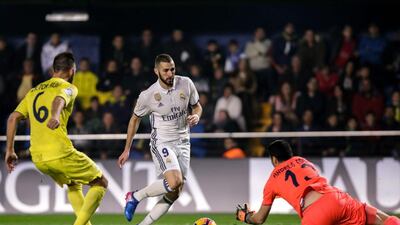 Real Madrid forward Karim Benzema, centre, vies with Villarreal’s goalkeeper Aitor Fernandez. Biel Alino / AFP