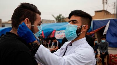 An Iraqi student shows an anti-government demonstrator how to wear a protective mask during a rally in the southern Iraqi city of Basra. AFP