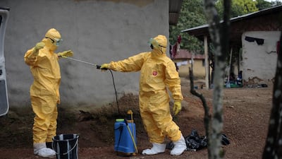 Mr Kamara, left, is sprayed by his co-worker, Konah Deno, after they load six patients suspected to have been infected by the Ebola virus into their ambulance in the village of Freeman Reserve. Both men are donning their yellow protective suits and eye goggles.