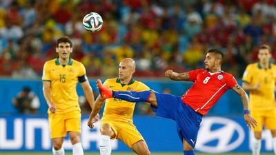 Arturo Vidal, right, of Chile, reaches to kick the ball against Mark Bresciano, centre, of Australia as Mile Jedinak, left, looks on during their World Cup Group B match on Friday night in Cuiaba. Brazil. Phil Walter / Getty Images
