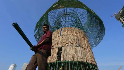 In this Thursday, Dec. 15, 2016 photo, Haloluwage Don Nanayakkara, left, carries a steel rod with another worker as they try to build an enormous, artificial Christmas tree on a popular beachside promenade in Colombo, Sri Lanka. The idea for the tree came from this Buddhist driver at Colombo’s port who makes decorations in his spare time. Hundreds of Sri Lanka’s port workers and volunteers are struggling to put up the towering Christmas tree in time for the holidays. The majority-Buddhist nation is aiming to beat the world record for the tallest, artificial Christmas tree as a show of multicultural respect. But twice the construction deadline was missed, and now organizers hope to erect the tree on Christmas Eve. The Catholic Church has criticized the $80,000 price tag as a waste of money that is better spent helping the poor. (AP Photo/Eranga Jayawardena)