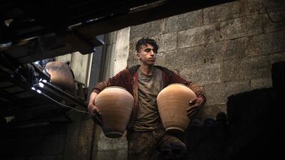 A son of Palestinian potter Sid Atallah carries dry clay pots at the family workshop in the central Gaza Strip. AFP
