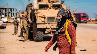 A woman walks past a US military armoured vehicle in the town of Tal Tamr along the M4 highway in the northeastern Syrian Hasakeh province, near the border with Turkey. AFP