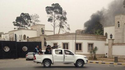 Armed men aim their weapons from a vehicle as smoke rises in the background near Libya’s General National Congress in Tripoli on May 18, 2014. Heavily armed gunmen stormed into Libya’s parliament on Sunday after attacking the building with anti-aircraft weapons and rocket-propelled grenades, witnesses and residents said. Reuters