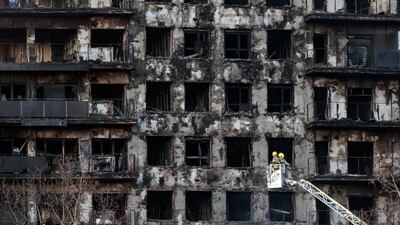 Spanish firefighters check the facade of a building after a fire in Valencia. The fire broke out in a residential building on February 22, leaving four dead and 19 missing. EPA