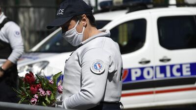 A police officer holds flowers brought by people to the scene of the attack in Rambouillet, south-west of French capital Paris. AFP