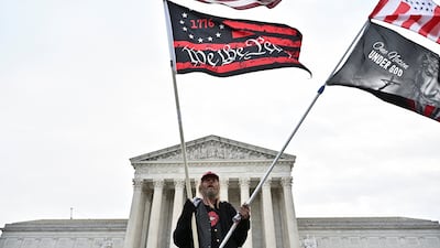 A man waves American and protest flags in front of the US Supreme Court. Reuters