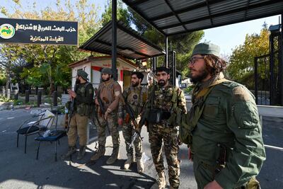 Anti-government fighters stand guard outside the Baath Party’s office in Damascus on Monday, after rebels had taken control of the Syrian capital. AFP