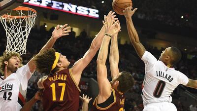 Damian Lillard, right, goes for a rebound over Cleveland's Kevin Love, second right, and Anderson Varejao, second left, in Portland's NBA victory on Tuesday night. Steve Dykes / Getty Images / AFP / November 4, 2014