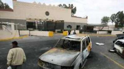 A man walks past damaged vehicles in front of the main entrance of the US Embassy in Sana'a.