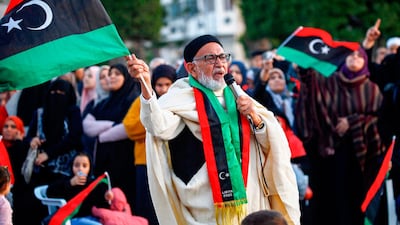 A man holding up a Libyan national flag and wearing a matching scarf speaks in a microphone in the Martyrs' Square in the GNA-held capital Tripoli on December 27, 2019. AFP