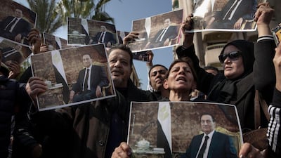 Supporters of ousted President Hosni Mubarak hold posters with his photograph near the cemetery where he will be buried. AP Photo