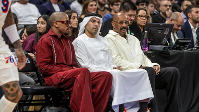 Mohamad Khalifa Al Mubarak, Chairman of the Department of Culture and Tourism Abu Dhabi, centre, and comedian Steve Harvey, right, watch the game from court side.