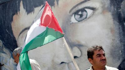A demonstrator holding a Palestinian flag stands in front of a mural during a protest against Israel's plan to annex parts of the occupied West Bank, in Gaza City. Reuters
