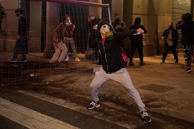 A demonstrator throws stones against police during clashes in downtown Barcelona, Spain. AP Photo