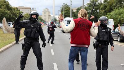 A member of the police gestures as demonstrators attend a protest against government measures to curb the spread of the Covid-19 in Berlin, Germany. Reuters