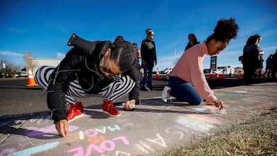 Latisha Hardy and daughter Yvonne Shepherd write notes in chalk on the sidewalk at the memorial. Reuters