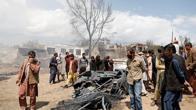 Men inspect a burnt car after an overnight fire, on the outskirts of Kabul. Reuters