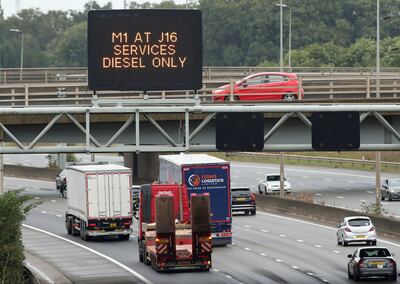 Lorries pass a sign warning that petrol has run out at a station near Luton on the M1 motorway in England. Reuters