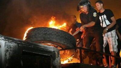 A Tunisian firefighter tries to extinguish a burning tyre on top of a truck after it was set on fire by radical Islamists protesters during overnight riots.