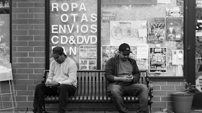 Two men sit on a streetside bench. While it would make for an ideal place to spark up a conversation with a stranger, the two men stare into their hands. Pickersgill's photos articulate how removed from our immediate world we’ve become in an effort to stay connected. Courtesy Eric Pickersgill